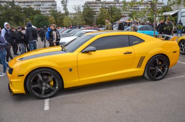 Kaput Chevrolet Camaro 'nun kaslı arabasındaki siyah yarış çizgileriyle özdeşleştirilmiş canlı sarı klasik 1969 modelinden esinlenilmiş retro modern bir tasarım.