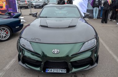 Siyah kapüşonlu, koyu yeşil Toyota Supra. İki kapılı spor araba. Uzun kapüşonlu ve şekillendirilmiş vücut hatları olan cesur, agresif bir tasarım.