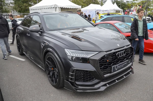 Koyu gri Audi RS Q8 özel vücut kiti ve turuncu iç aksanlı bir açık hava etkinliğinde park halinde.