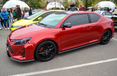 Pürüzsüz Scion TC, parlak kırmızı kaplamalı kompakt spor coupe, siyah çoklu alaşımlı tekerlekler, ve zıt siyah çatı, ona özel, agresif görünüm verir