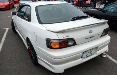 Beyaz Toyota Sprinter Trueno popüler Japon Yurt İçi Marketi (JDM) spor coupe, 90 'ların Japon spor arabalarının ayırt edici özelliklerinden biri olan gösterişli, gösterişsiz tasarımını sergiliyor