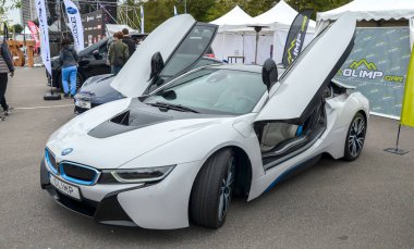 Çarpıcı beyaz BMW i8 hibrit spor araba ikonik makas kapıları ile sunuluyor. Gösterişli çizgiler ve mavi aksanların yer aldığı fütüristik ve aerodinamik tasarım vurgulandı