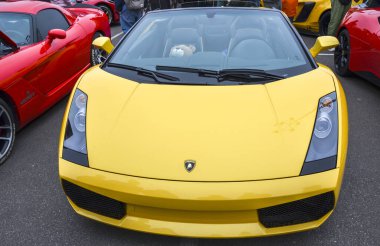 Canlı sarı Lamborghini Gallardo Spyder, gösterişli çizgileri, siyah yumuşak bluzu ve görünür performans tekerlekleri olan sembolik bir İtalyan spor arabası.