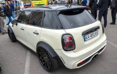 Özelleştirilmiş krem renkli siyah çatılı MINI Cooper, siyah çamurluk fişekleri, çok dilli siyah tekerlekler, ve sarı renkli sis ışıkları.