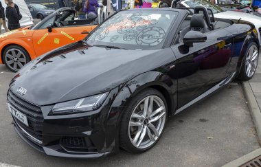 Parlak siyah Audi TT Roadster, TT siluetini tanımlayan ikonik eğimli çatı çizgisini muhafaza ediyor, seleflerine kıyasla daha agresif ön ızgara.