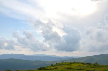 Yuvarlanan yeşil tepeler dramatik, bulutlarla dolu gökyüzünün altındaki uzak dağlara kadar uzanıyor, sakin, geniş bir ruh hali yaratıyor doğa ve açık hava macera temaları için mükemmel. Svydovets, Karpatlar, Ukrayna