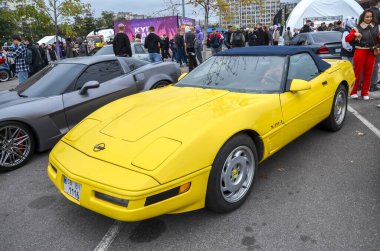 Amerikan spor araba ikonu klasik sarı Chevrolet Corvette C4 üstü açılır, yumuşak kapaklı ve ikonik farlar açık hava araba fuarında sergileniyor.