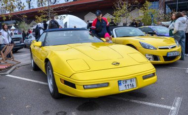 Amerikan spor araba ikonu klasik sarı Chevrolet Corvette C4 üstü açılır, yumuşak kapaklı ve ikonik farlar açık hava araba fuarında sergileniyor.