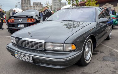 Chevrolet Caprice sedan. Ön ızgara, dikdörtgen farlar ve krom tekerleklerdeki beyaz duvar lastikleri klasik Amerikan otomotiv tasarımını çağrıştırıyor.