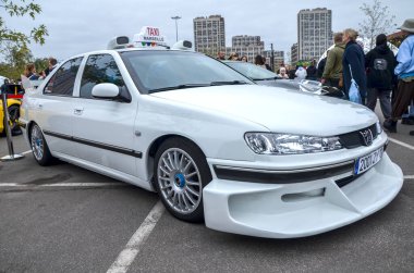 Marsilya 'dan gelen ikonik taksi arabasına benzeyen yüksek özelleştirilmiş beyaz Peugeot 406 sedan bir açık hava etkinliğinde sergilenmektedir.