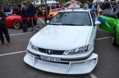 Marsilya 'dan gelen ikonik taksi arabasına benzeyen yüksek özelleştirilmiş beyaz Peugeot 406 sedan bir açık hava etkinliğinde sergilenmektedir.