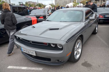 Gösterişli gri Dodge Challenger ikonik Amerikan kaslı arabası yan tarafında klasik yarış şeritleri güçlü kaput tasarımı ve somut retro performansları barındırıyor.