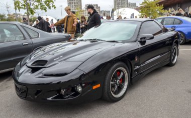 Gösterişli, siyah Pontiac Firebird Trans Am. İkonik aerodinamik tasarımı, kendine özgü kaput kepçesi ve farları olan klasik bir Amerikan kaslı arabası.
