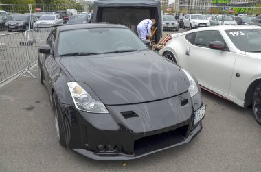 Performansı ve tasarımı ile tanınan popüler bir Japon spor otomobili olan siyah Nissan 350Z, açık hava otomobil etkinliğinde sunulmaktadır.