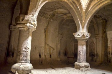 Geghard Manastırı 'nın iç kısımları, heybetli kemerleri destekleyen iki büyük ve süslü taş sütunla kısmen kayalara oyulmuştur ve uçurumlarla çevrilidir. Ermenistan