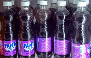 Rafta Fanta Sıfır dolu. Üzümlü Soda Şişeleri. Koyu mor sıvı ve beyaz başlıklı parlak mor etiketler göze çarpar.