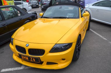 Sarı BMW Z4 üstü açık, siyah yumuşak üstüyle şık Alman roadster kırmızı fren kalibreli siyah tekerlekleri var, sportif ve birinci sınıf çekiciliğini vurguluyor.