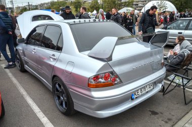 Gümüş Mitsubishi Lancer VIII Sedan. İkonik büyük arka kanadını ve agresif rali esinlenilmiş stilini açık hava araba fuarında sergiliyor.