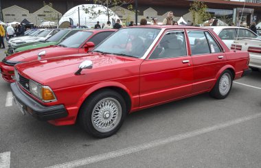 Klasik kırmızı Nissan Bluebird 910 sedan vintage Japon aile arabası güvenilir ve şık bir otomotiv tasarımını temsil ediyor.