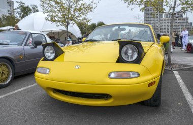 Açık sarı Mazda MX-5 Miata NA üstü açılabilir ikonik farlarıyla sevgili Japon roadster 'ı zamansız çekiciliğini ve karakterini sergileyerek