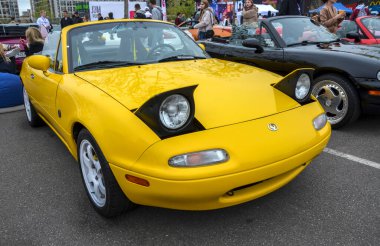 Açık sarı Mazda MX-5 Miata NA üstü açılabilir ikonik farlarıyla sevgili Japon roadster 'ı zamansız çekiciliğini ve karakterini sergileyerek