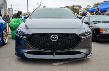 Gösterişli koyu gri Mazda 3 hatchback 4. nesil, özel çoklu konuşmalı alaşımlı tekerlekler parlak sarı fren kalibreli ve sportif düşük duruşu var.