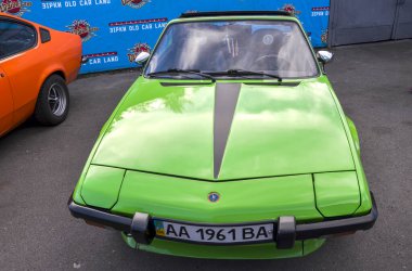 Canlı, yeşil Fiat X19, klasik orta-motorlu İtalyan spor arabası, konik düşük askılı, kama şeklindeki tasarımı, fal lambaları ve entegre siyah tamponlar.