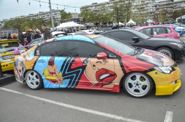 Kyiv araba festivalinde gösterilen stilize edilmiş kadın karakterlerin yer aldığı özenle hazırlanmış bir pop-art grafik ambalajlı Honda Civic sedan.