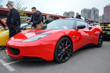 Çarpıcı kırmızı Lotus Evora spor arabası, egzotik İngiliz orta motor coupe hafif tasarımı, çevik kullanımı ve sürücü odaklı performansı ile ünlüdür.