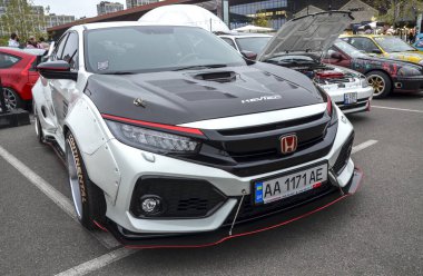 Son derece modifiye edilmiş, geniş gövdeli siyah kapüşonlu beyaz Honda Civic sedan açık hava araba fuarında sergileniyor.