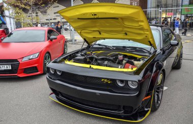 Güçlü motoru ve çarpıcı sarı aksanları göstermek için kaputu açık siyah Dodge Challenger RT güçlü araba, açık hava araba fuarı veya etkinliği park