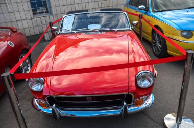 Canlı kırmızı klasik MG MGB iki kapılı üstü açık araba İngiliz spor araba tasarımının zamansız zarafetini ve nostaljik çekiciliğini yakalıyor.