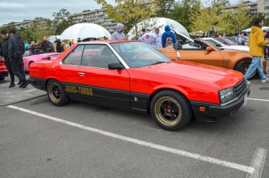 Nadir ve klasik kırmızı 1981 Nissan Skyline R30 coupe siyah aksanlı Japon otomotiv mühendisliğinin önemli bir dönemini temsil etmektedir.