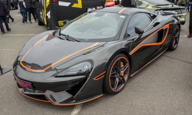 McLaren 570S, turuncu aksanlı gri bir süper araba, günlük kullanıma odaklanmış lüks bir spor araba olarak bilinir.