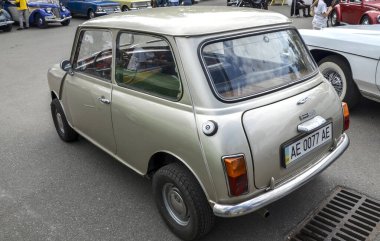 Klasik bej 1965 Austin Mini kompakt arabası, ikonik yuvarlak farları ve kompakt tasarımıyla, İngiliz mühendisliğinin ruhunu mükemmel bir şekilde yakalıyor.