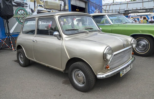 Klasik bej 1965 Austin Mini kompakt arabası, ikonik yuvarlak farları ve kompakt tasarımıyla, İngiliz mühendisliğinin ruhunu mükemmel bir şekilde yakalıyor.