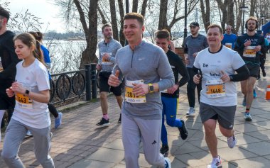 Atletizm teçhizatındaki koşucular, bitiş çizgisine doğru ilerlerken, takım çalışmalarını, formaları ve kutlamaları sergileyerek anı paylaşıyorlar.