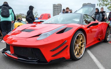 Vibrant kırmızı Ferrari 458 Italia spor araba, çarpıcı bir Prior Design geniş gövde aerodinamik kiti ile modifiye, açık hava araba etkinliği park edilir