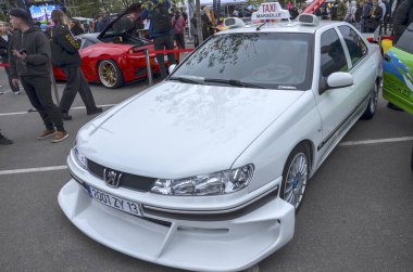 Beyaz modifiye edilmiş Peugeot 406 sedan. Geniş gövde kiti ve Taxi Marsilya tabelası Fransız aksiyon komedi filmindeki ikonik film arabasının detaylı bir kopyası.