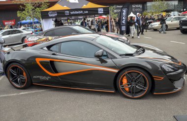 Koyu gri McLaren 570S yüksek performanslı lüks spor araba. Özel yapım turuncu plastik ambalajlı ve aksanlı. Yan profil boyunca çizgiler de var.