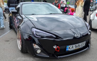 Saldırgan bir şekilde modifiye edilmiş siyah Toyota GT86 coupe geniş gövdeli aero takımı, genişletilmiş çamurluk fişekleri ve siyah özel yapım tekerler üzerine çarpıcı bir şekilde alçaltılmış duruş.