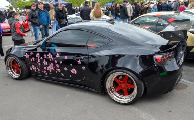 Saldırgan bir şekilde modifiye edilmiş siyah Toyota GT86 coupe geniş gövdeli aero takımı, genişletilmiş çamurluk fişekleri ve siyah özel yapım tekerler üzerine çarpıcı bir şekilde alçaltılmış duruş.