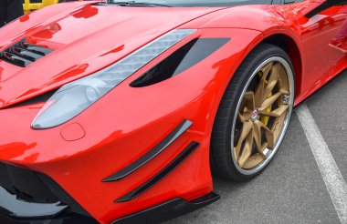Parlak, kırmızı spor arabalar Ferrari 458 Italia ön çamurluk, gösterişli parlak far, siyah hava delikleri, ve düşük profilli altın renkli çoklu tekerlek
