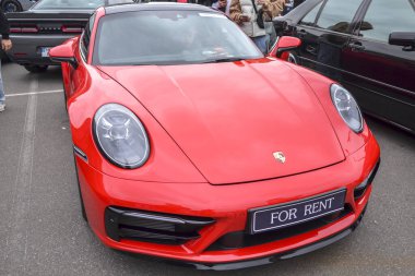 Modern kırmızı Porsche 911 (992 nesil) açık havada park edilmiş spor araba, lüks ve performans simgesi.