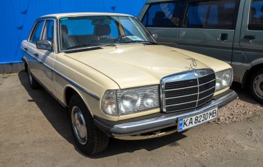 Klasik krem Mercedes-Benz W123 tam boy sedan, ikonik yuvarlak farlar, krom ızgara ve uzun ömürlü Alman kalitesinin geleneksel kutu tasarımı.