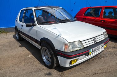 Çarpıcı beyaz Peugeot 205 GTI efsanevi üç kapılı Fransız arabası 1980 'lerin sıcak kapak döneminin simgesi olan çevik ve saf sürüş dinamikleri ile kutlanıyor.