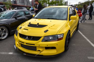 Çarpıcı, saldırganca modifiye edilmiş sarı Mitsubishi Lancer Evolution IX performans sedan, havalandırma kaputu, geniş ön ayırıcı ve kara borsa tekerlekleri var.