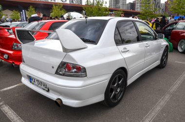 Beyaz Mitsubishi Lancer Evolution VII geniş ön tampon hava girişiyle ve ayarlanabilir yükseklik açısı fonksiyonel ve agresif estetik ile tanımlanan arka spoiler