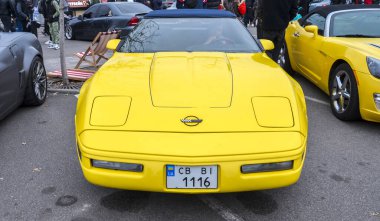 Klasik sarı Chevrolet Corvette C4 sembolik Amerikan spor arabası, belirgin açısıyla, kama şekliyle 1980 ve 90 'ların klasik kaslı araba tasarımını yakalıyor.