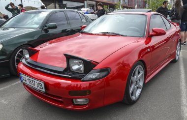 Canlı kırmızı Toyota Celica coupe, ön far, düşük profil ve sportif estetik 90 'ların Japon iç pazarındaki JDM performansının özünü mükemmel bir şekilde yansıtıyor.